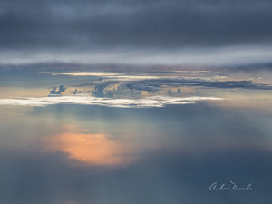 A spectacular photo of monsoon skies taken from a plane. Rain clouds above, a sun-soaked lake below and in the middle, clouds of varying shapes and hues. Prints available.
